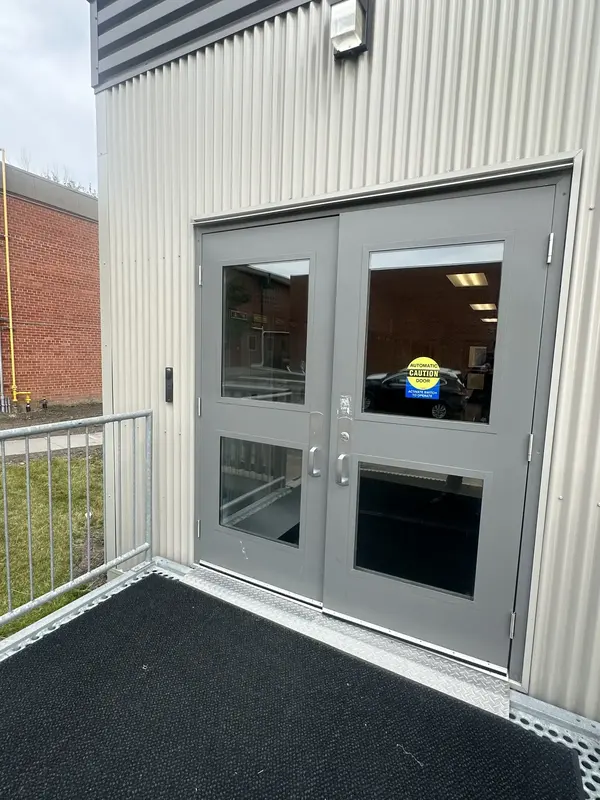 Video intercom installed beside secured double doors at a commercial entrance